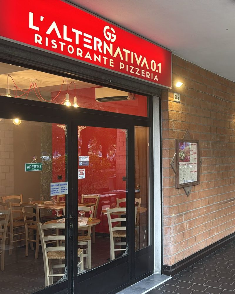 L'ingresso del locale con l'insegna rossa, sotto il portico